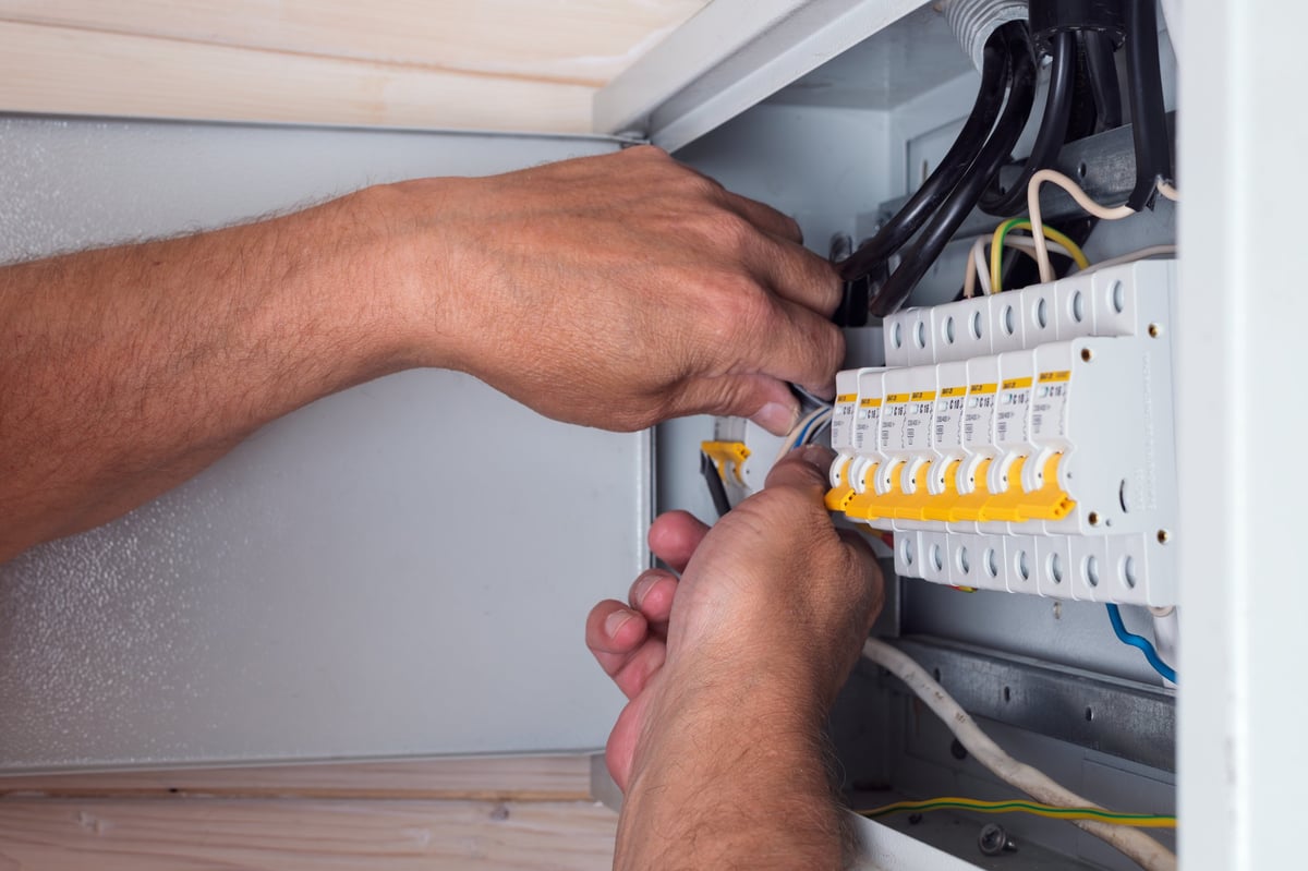 Electrician connecting cables in an open distribution board — CN Electrical panel upgrade and circuit installation in Chilliwack, BC