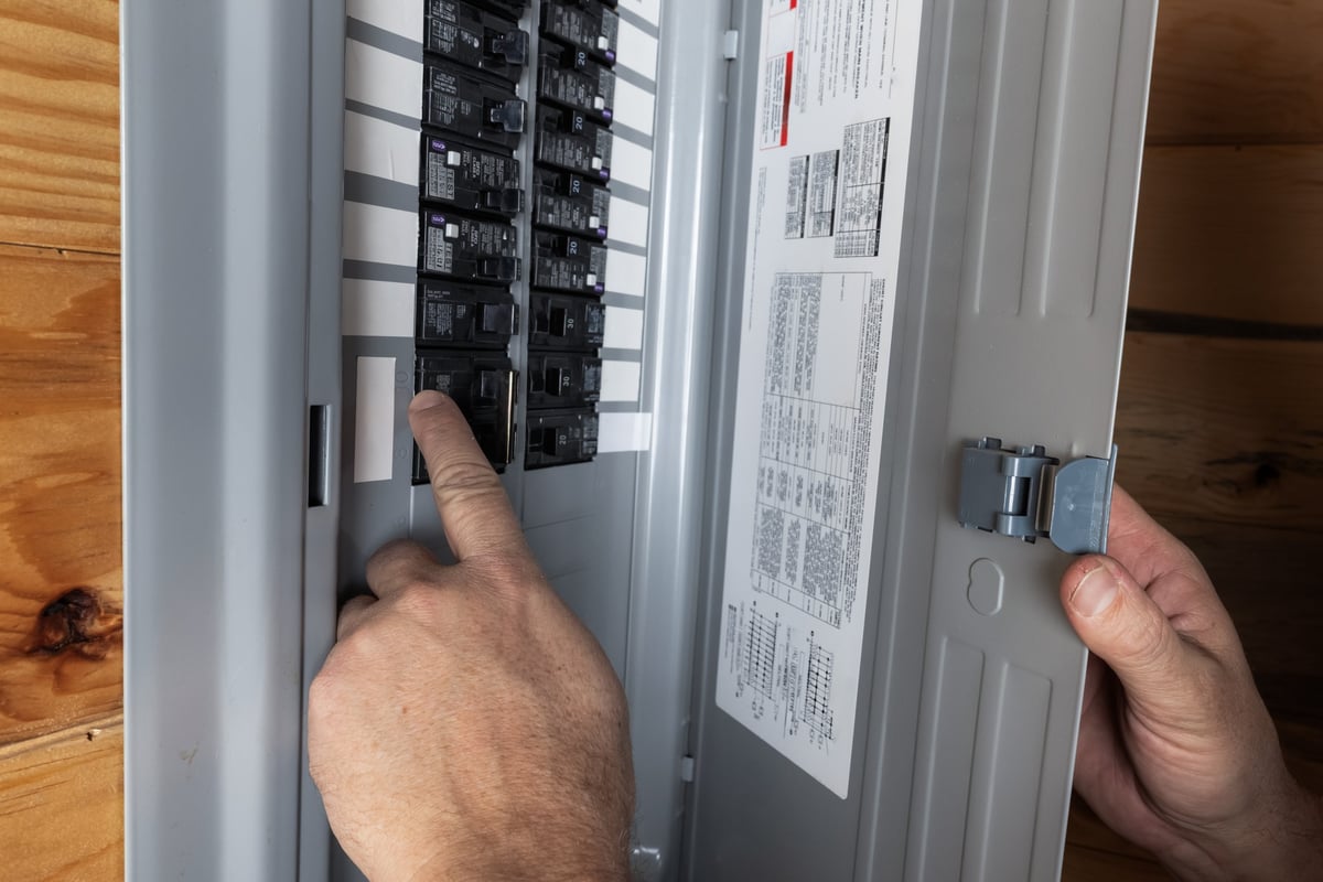 Close up of a homeowner inspecting electrical breakers in a residential panel — CN Electrical panel upgrade assessment in Chilliwack, BC